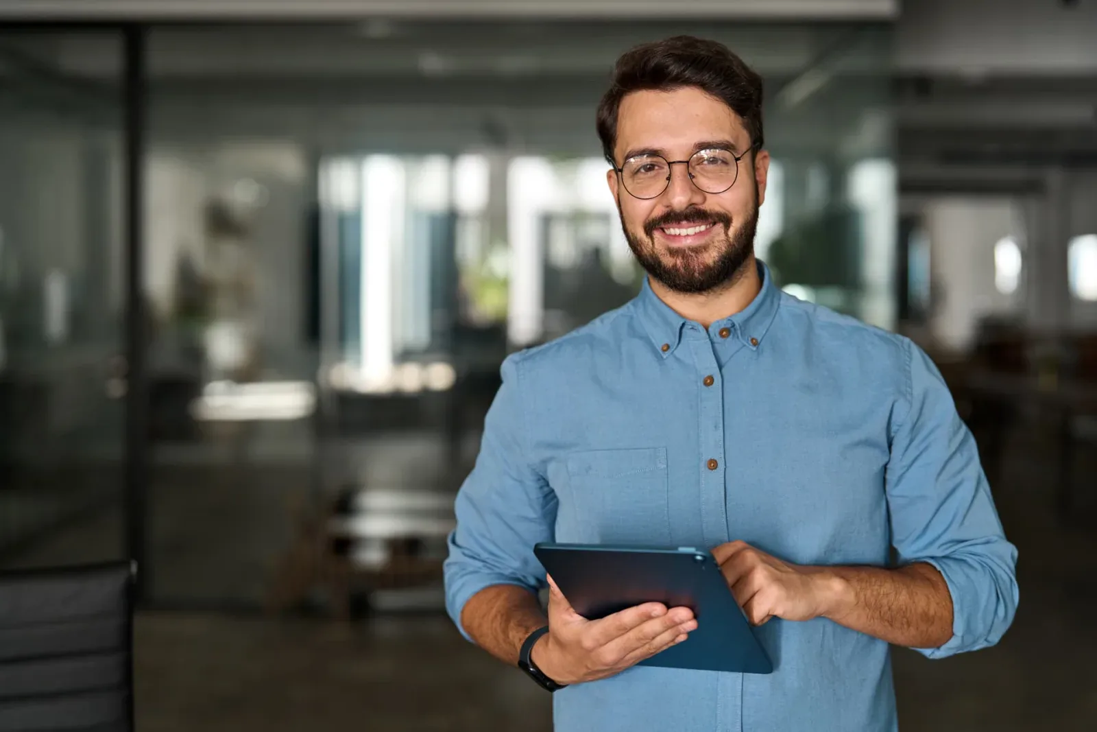 Profesional sonriendo con una tablet mientras usa la inteligencia artificial de Naaloo en la oficina