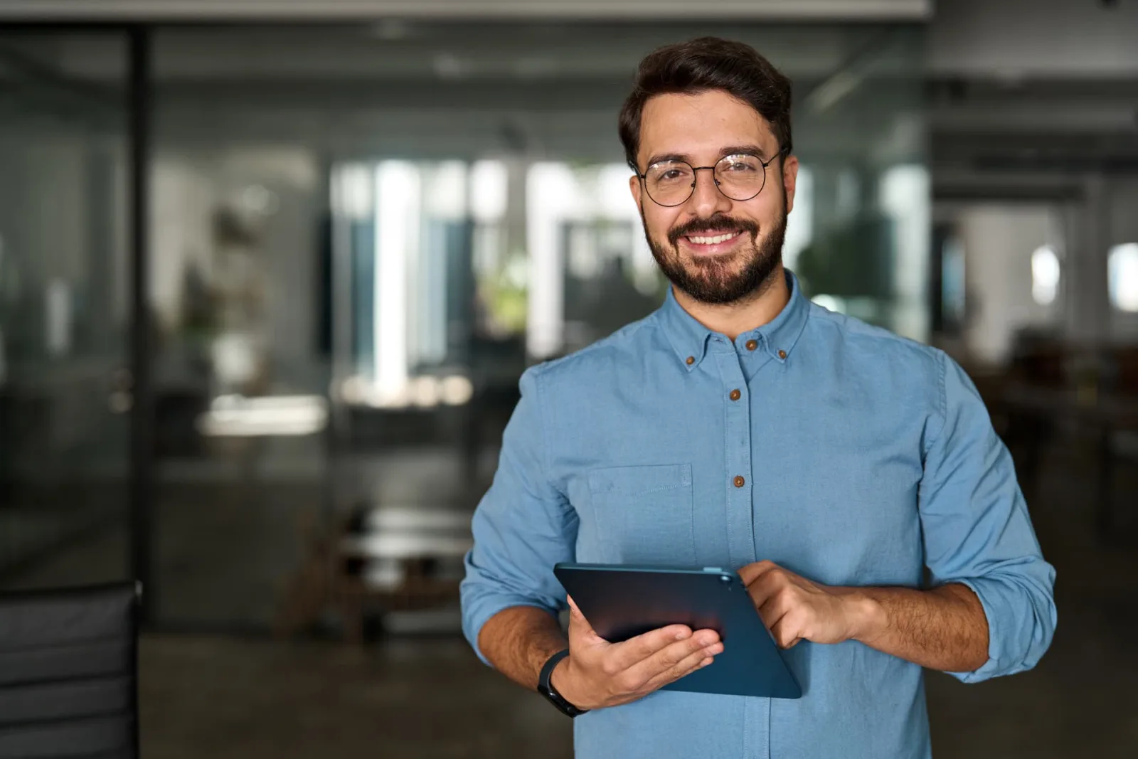 Profesional sonriendo con una tablet mientras usa la inteligencia artificial de Naaloo en la oficina