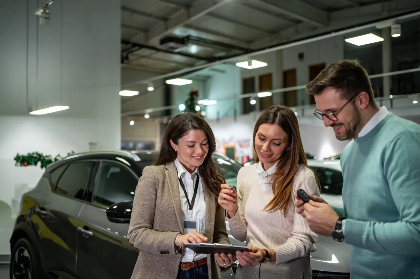 Asesora de ventas mostrando opciones de financiación a una pareja en el showroom de la concesionaria